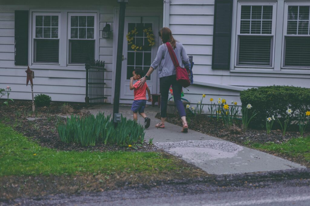 A mom and her son walk to their home in springtime, showcasing a garden and welcoming atmosphere.