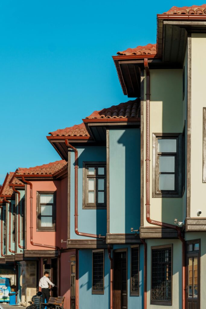 Row of colorful traditional houses with red roofs under a clear blue sky.