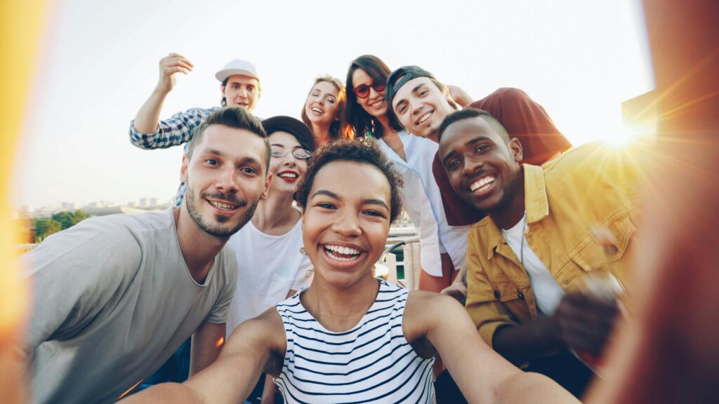 A happy group of young friends taking a selfie during a rooftop party on a sunny day.