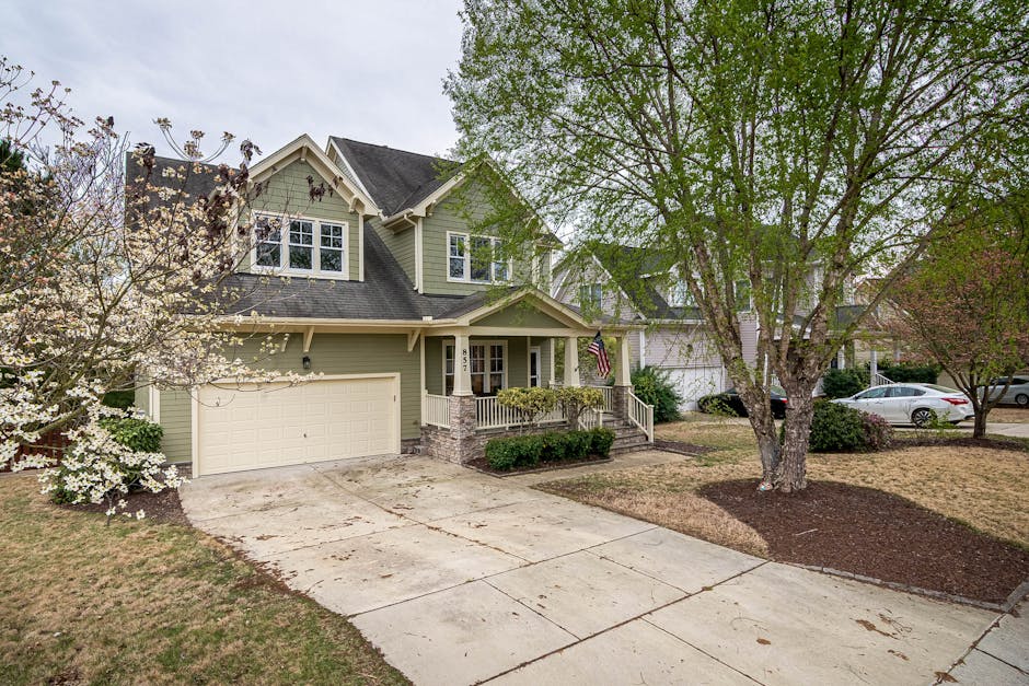 A picturesque suburban home with a lush front yard, driveway, and trees.