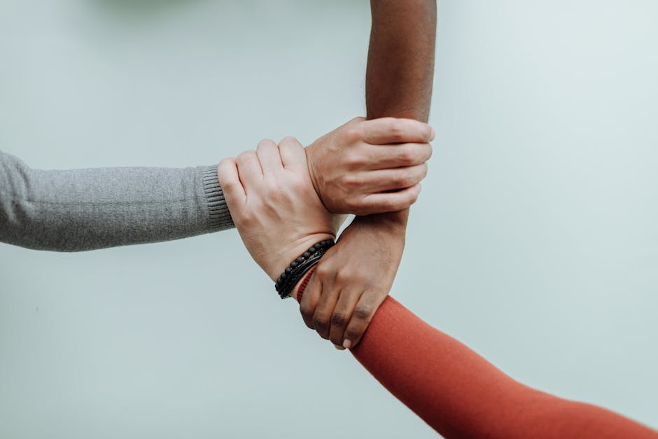 Three individuals' hands connected in a symbol of teamwork and diversity.