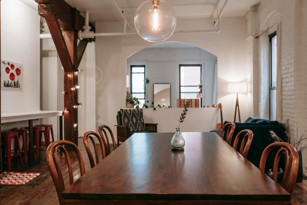 Wooden table with chairs placed in cozy room with white brick wall and garland on beam