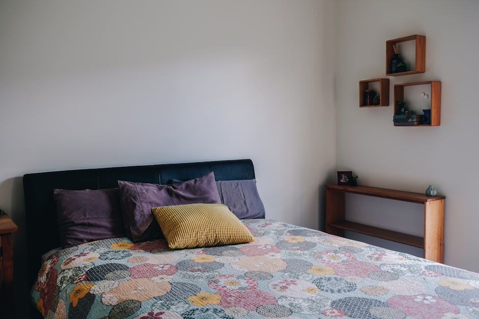 Soft pillows placed on comfortable bed with minimalist interior and wooden shelves in morning