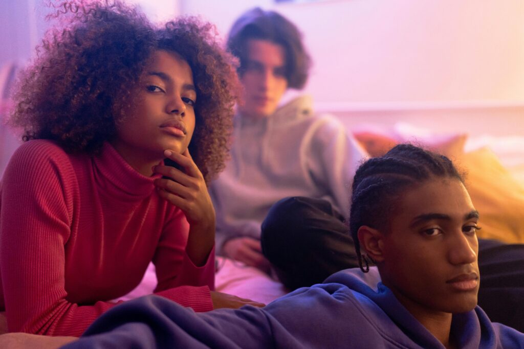 A captivating portrait of three teenagers in vibrant lighting, showcasing youth and diversity.