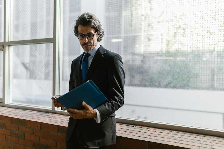 Focused businessman in suit and tie reading documents indoors with natural light.