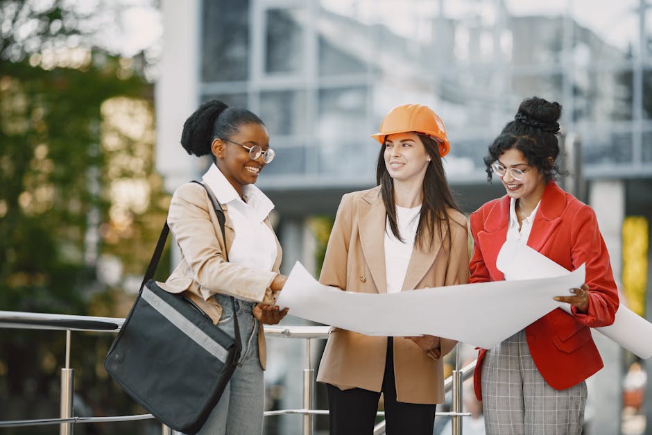 Three women collaborating outdoors on architectural plans, showcasing teamwork and diversity.