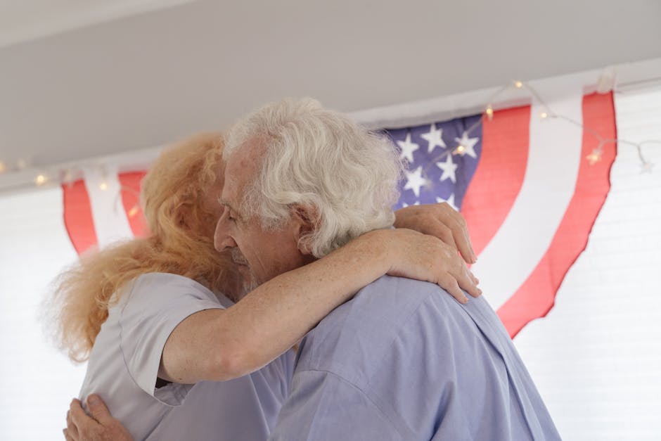 Senior couple embracing with American flag backdrop, celebrating togetherness and freedom.